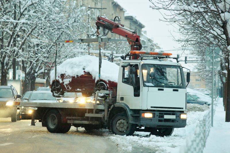 Laweta w Koninie transportuje unieruchomiony samochód w zimowych warunkach na drodze
